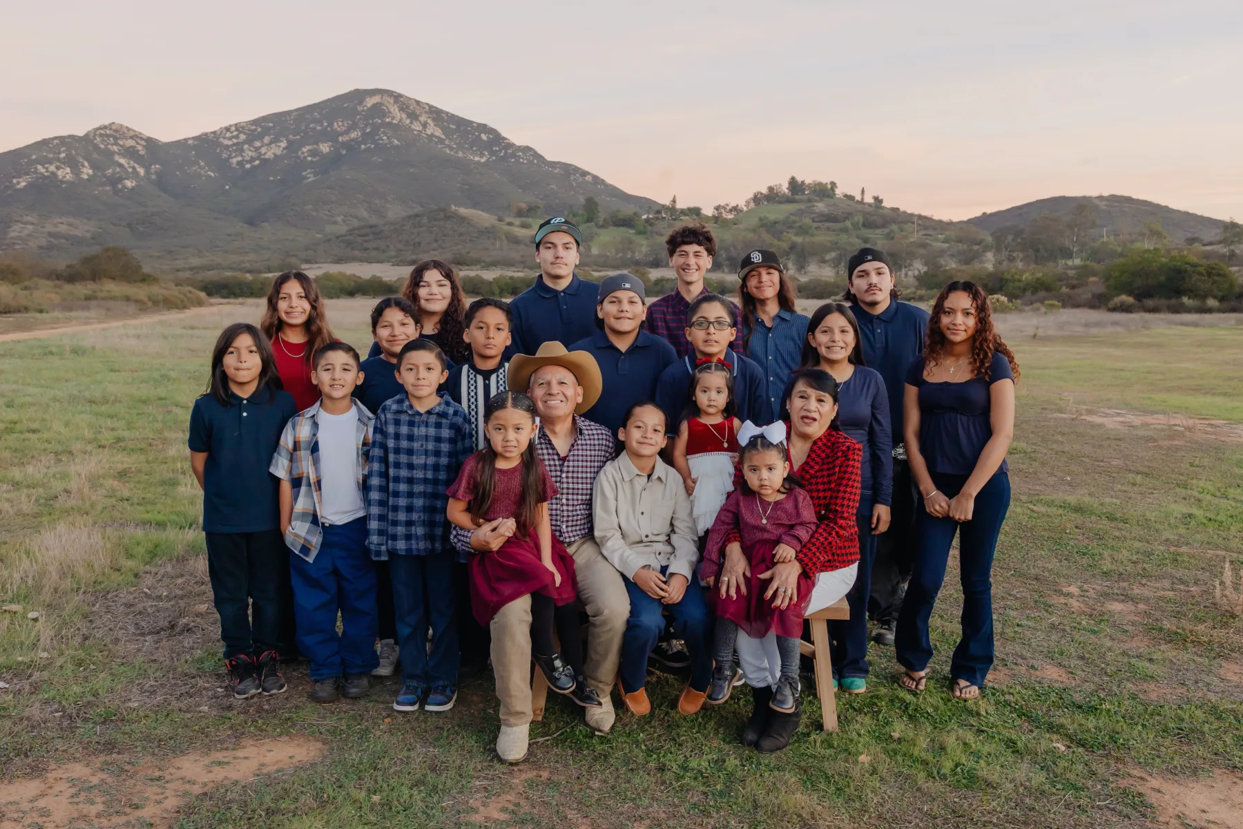 Extended family in a meadow with mountains behind, JSOLOVISUALS