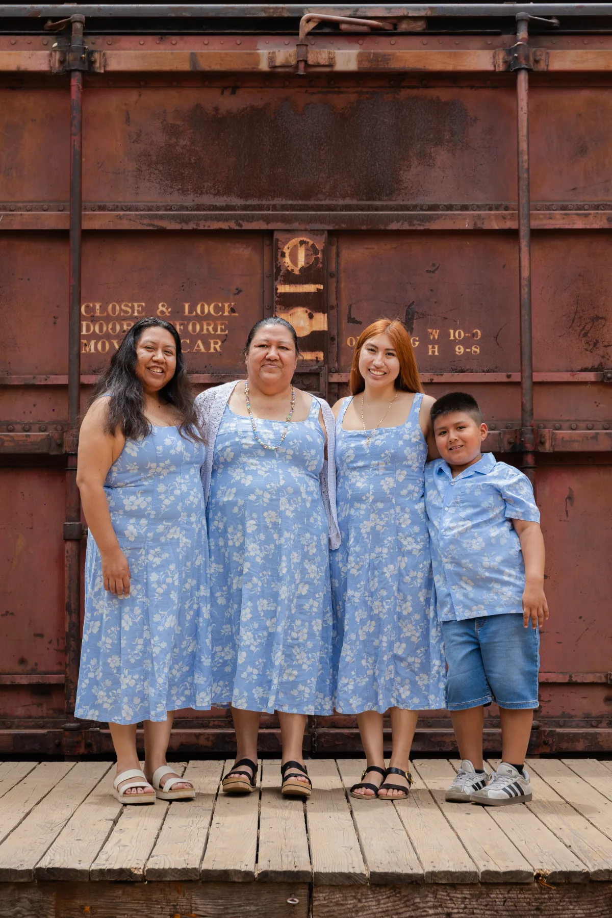 Three women and a boy in blue florals by a vintage rail car, JSOLOVISUALS