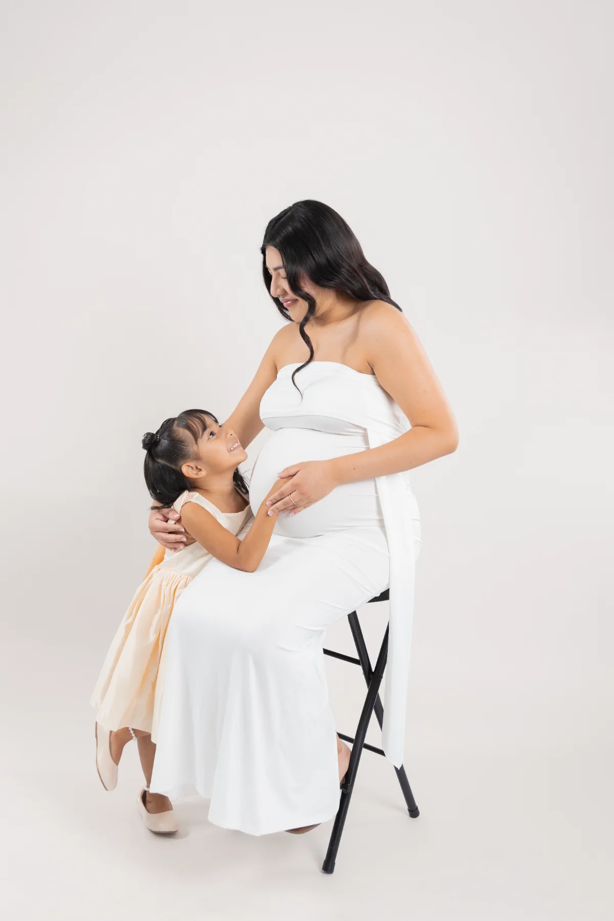 Daughter hugging mom's belly during a maternity session, JSOLOVISUALS studio in Poway, CA