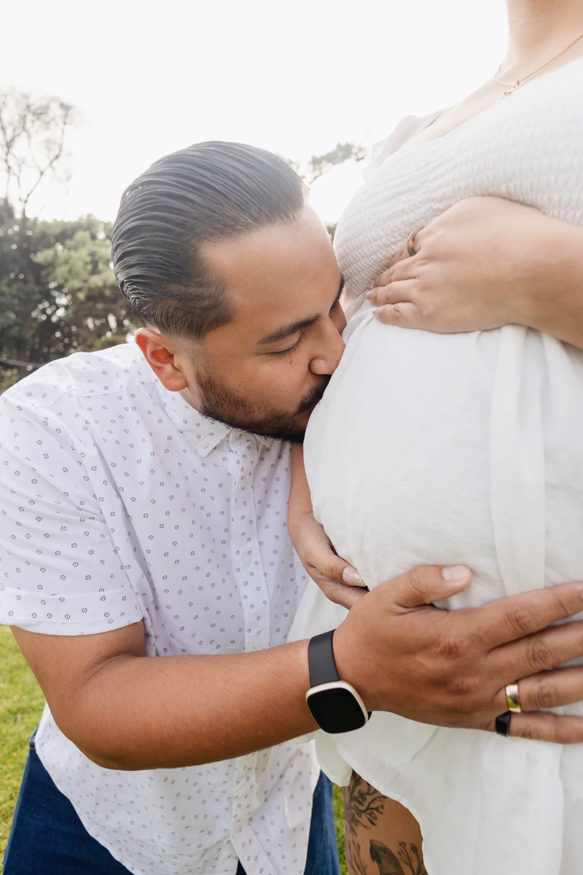 Dad kissing the bump during an outdoor maternity session in San Diego