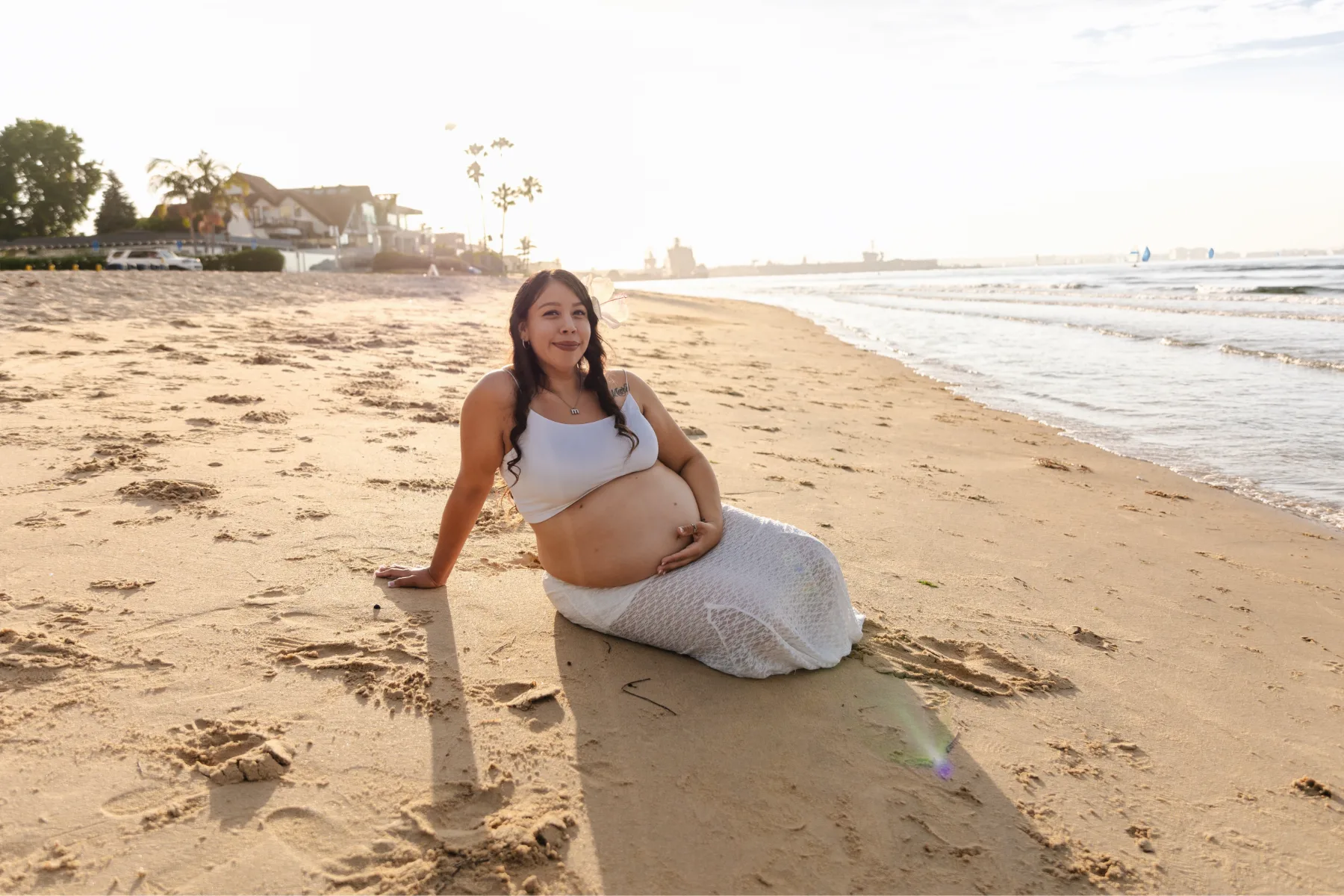 Maternity portrait sitting on the sand at golden hour, San Diego