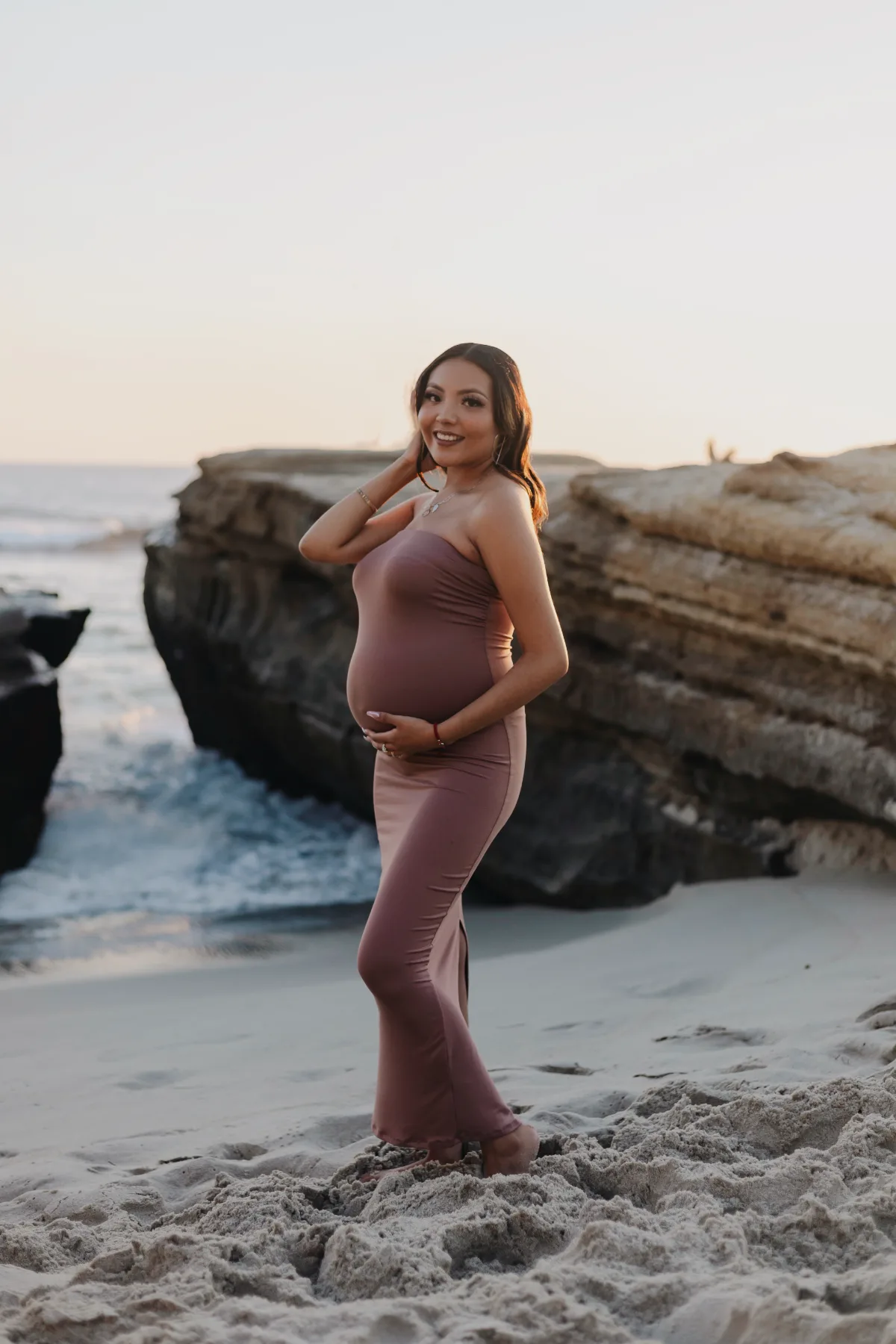 Maternity portrait in a mauve gown on the beach at golden hour